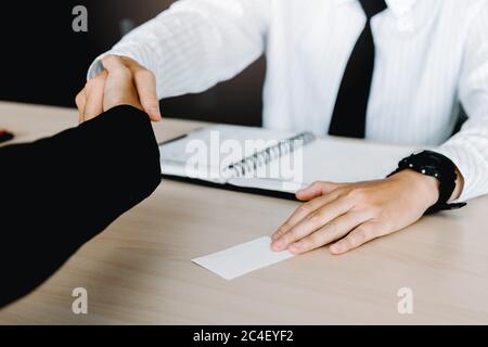 Business people passing blank business card and shaking hand to colleague. Stock Photo