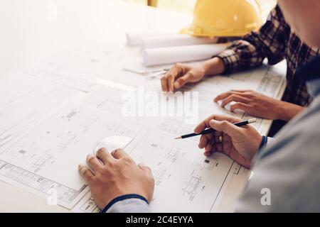 Architects working with blueprints and discussing project together at the meeting in the office. Stock Photo
