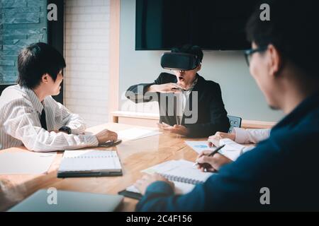 Asian business team using virtual reality VR headset in office meeting. Stock Photo