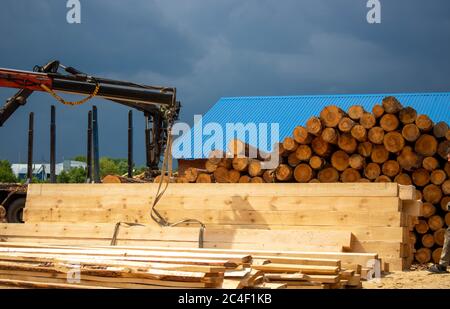 Logging, sawmill. Manipulator for loading wood. The loader of boards and logs works against the background of a stormy sky. Stock Photo