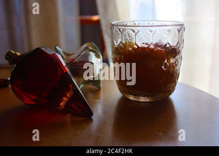 glass with orange a candle with a candle holder and a red perfume made in ruby ​​on a wooden table Stock Photo