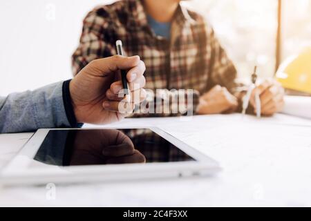 Male engineering using digital tablet with architectural plan on desk. Stock Photo