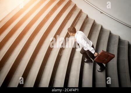 Businessman walking up on stairs and holding briefcase. Stock Photo