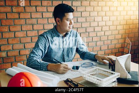 Architect working and examining blueprints for new project in new modern office. Stock Photo