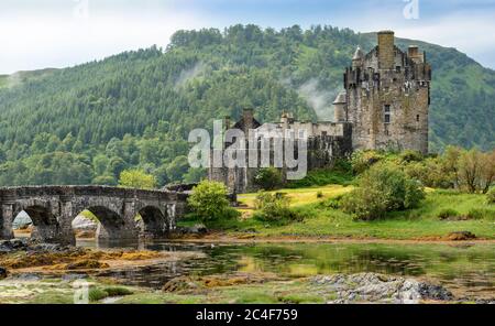 EILEAN DONAN CASTLE LOCH DUICH HIGHLAND SCOTLAND BRIDGE TO THE CASTLE  AFTER A SUMMER DOWNPOUR OF RAIN AND THUNDER MIST OVER THE HILL Stock Photo