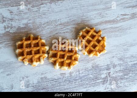 Small round delicious soft belgian waffles on cutting board. Fresh belgian waffles with berries and caramel sauce top view. Stock Photo
