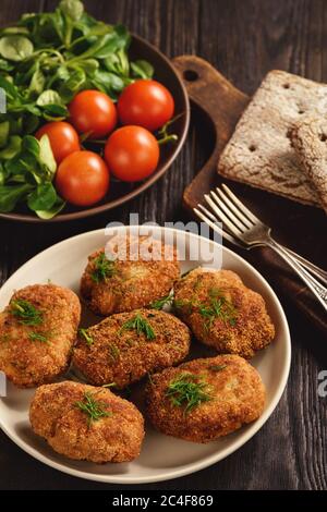 Fried meat cutlets, tomatoes and salad on wooden background. Stock Photo