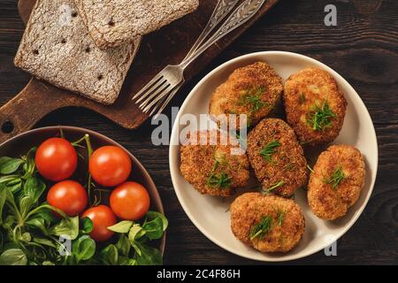 Fried meat cutlets, tomatoes and salad on wooden background. Stock Photo