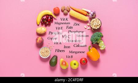 Fresh fruits and vegetables and their nutrition facts, on a pink background. Vegan food is rich in minerals, proteins, fats, and vitamins. Stock Photo