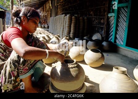A woman carves designs on earthen pots and vases. Colourful earthenware like pots, jars, and vases enhance the beauty of city households. Besides, it Stock Photo