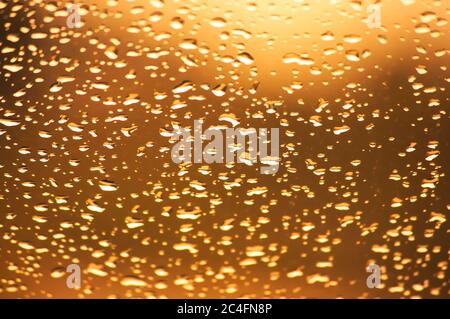 Fine raindrops create an orange abstract background on window glass Stock Photo