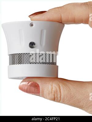 woman holding small smoke detector between fingers Stock Photo