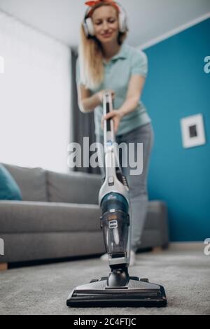 Mature housewife removing dust from carpet with vacuum Stock Photo