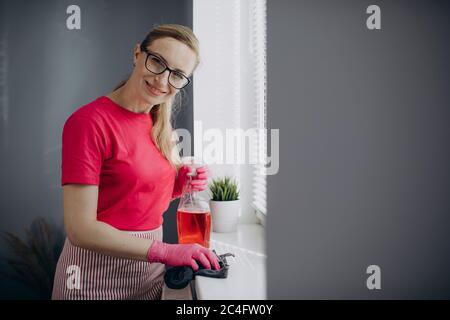 Woman using cloth and spray for cleaning windowsill Stock Photo