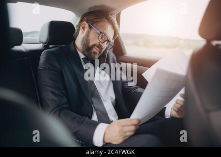 Man sitting in car with documents and talking on mobile Stock Photo