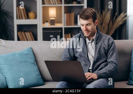 Handsome man using laptop during free time at home Stock Photo