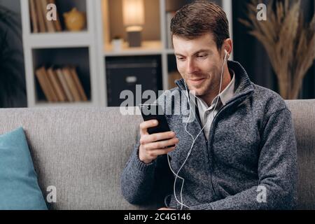 Cheerful man in earphones having video call on smartphone Stock Photo