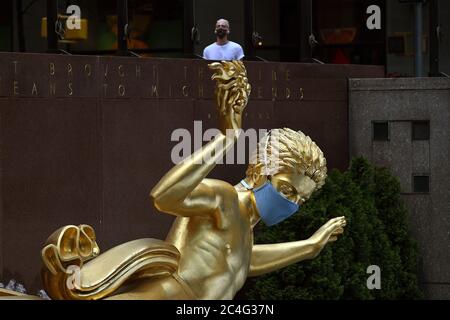 New York City, USA. 26th June, 2020. Prometheus, a 1934 gilded bronze sculpture by Paul Manship located in Rockefeller Plaza, is adorned with a blue face mask to promote Phase Two of New York City's reopening and encourage social distancing to stop the spread of COVID-19, New York, NY, June 26, 2020. (Anthony Behar/Sipa USA) Credit: Sipa USA/Alamy Live News Stock Photo