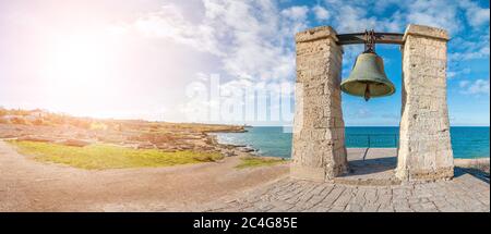 Big bronze bell on the sea shore in the ancient Greek city Chersonesus, Hersones in Sevastopol, Crimea. Copy space. Travel and relax concept. Stock Photo