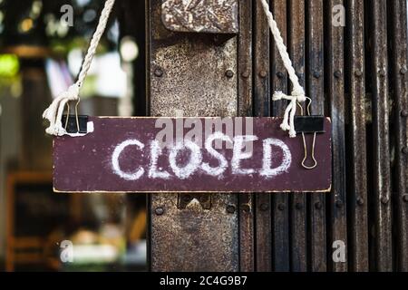 A Sign board of sorry we are closed hang on door of business shop with nature green background Stock Photo