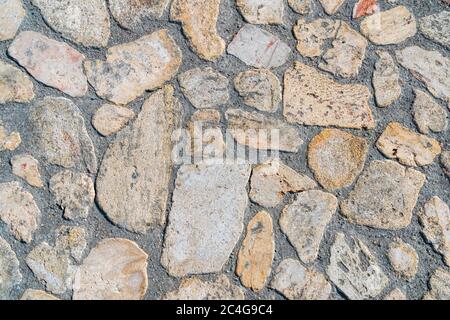 The road paved from wild paving stones of various shapes. Wild stone pavement floor. Irregular shapes pattern. Stock Photo