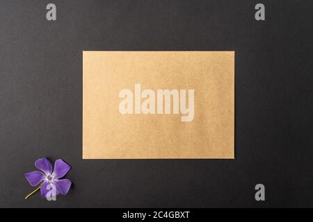 Brown craft envelope with violet flower isolated on black background with , blank copy logo space on black Stock Photo