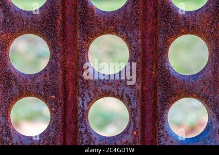 Texture of old rusty perforated metal. Round holes in a metal sheet closeup. Abstract hole background Stock Photo