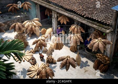 Hung Yen Province, Vietnam - May 27, 2020: Unidentified women who live in traditional village are weaving bamboo sticks to make bamboo products. Those Stock Photo