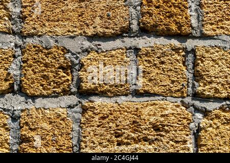 Wall texture of the stone shell yellow. Natural decorative building material. Close-up, background of a golden warm hue. Stock Photo
