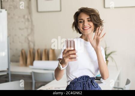 Young joyful woman with short curly hair in wireless earphones s Stock Photo
