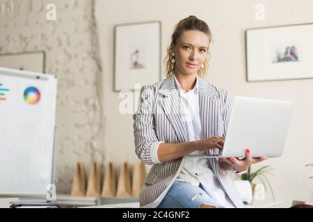 Young thoughtful woman in striped jacket and jeans sitting on de Stock Photo