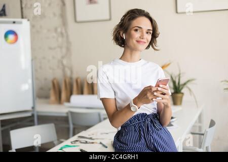 Young smiling woman with short curly hair in wireless earphones Stock Photo