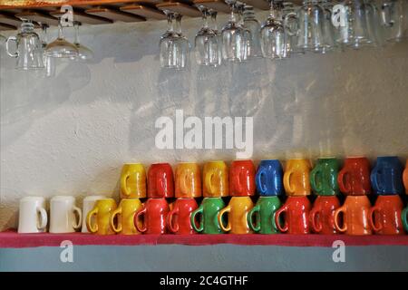 Rows of colorful coffee cups on a shelf in a coffee shop. Stock Photo