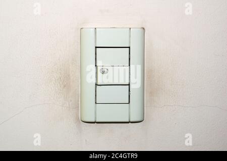 Dirty, old light switch on a cracked, weathered wall. Stock Photo