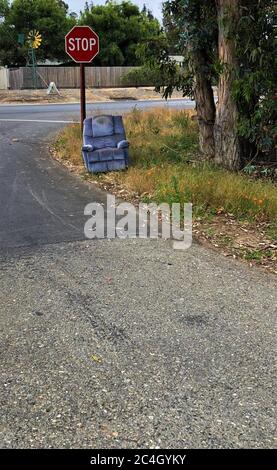 Abandoned chair left at stop sign along country road for anyone to take home and use, and it's free on the street for the taking Stock Photo