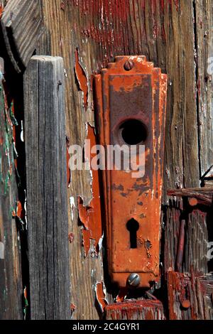 rugged wood door frames on inside of old barn door with peeling red paint on lock set, antique from the 1900's on Route 66 Stock Photo