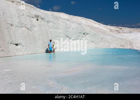 A man and boy stand in one of the thermal pools at the travertines, or Cotton Castle, at Pamukkale in Turkey. Stock Photo