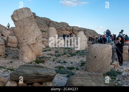 Tourists at the western platform at Mount Nemrut in Turkey. Stone statues located here include a Persian eagle god , Hercules , Antiochus and Zeus. Stock Photo