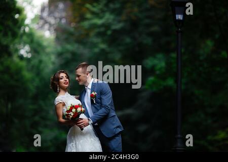 Fabulous young wedding couple posing in the park on the sunny day. Stock Photo