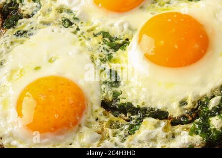 Fried eggs with spinach in a pan Stock Photo