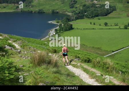 Fell runner descending towards Buttermere (lake) from Scarth Gap in the Lake District National Park and UNESCO World Heritage Site Stock Photo