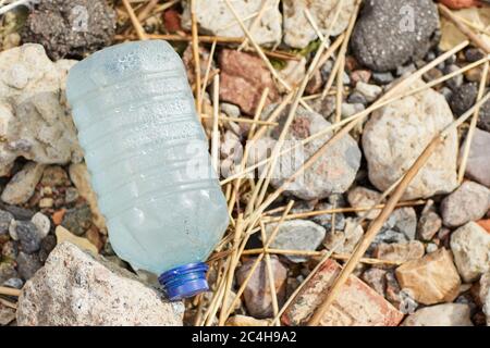 Close-up of big plastic bottle lying on the stones near the coastline Stock Photo