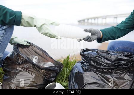 Close-up of volunteers cleaning nature from garbage they putting plastic bottles in rubbish bags Stock Photo