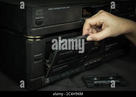 Woman hand inserting compact cassette tape in old player audio are retro technology Stock Photo