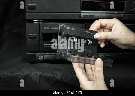 Close up women hand holding a cassette tape compact at old played audio tape background Stock Photo