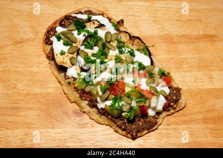 HOME MADE MIDDLE EASTERN FLAT BREAD WITH GRILLED EGGPLANT, ZATAR, CUCUMBER, TOMATO ONION, PUMPKIN SEEDS, PARSLEY AND YOGURT Stock Photo