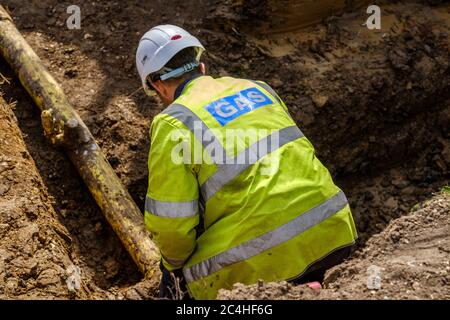 Gas engineer inspects pipe in trench on construction site Stock Photo