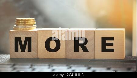 More word on wooden cubes on computer keyboard and coins. Investment and saving financial concept. Selective focus Stock Photo