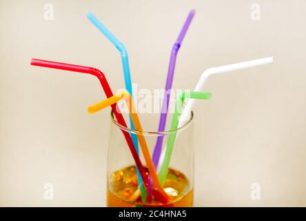 Multicolored tubes in a glass with a yellow drink - side view Stock Photo