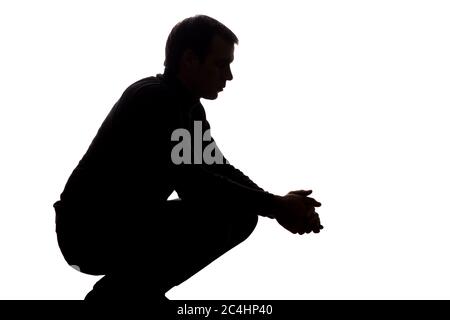 Portrait of a young man squatted down, side view - silhouette Stock Photo